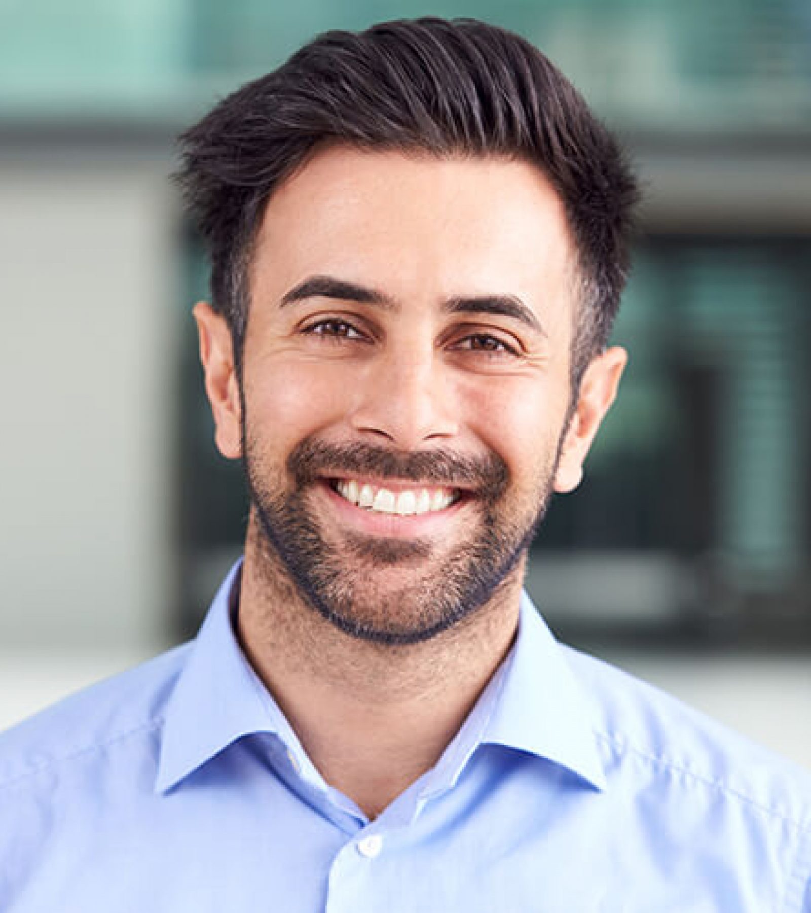 portrait-of-smiling-businessman-standing-in-lobby-3QPCMXE.jpg